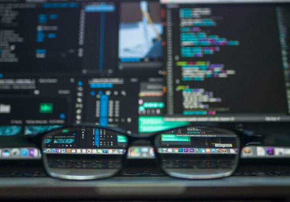 Eyeglasses reflecting computer code on a monitor, ideal for technology and programming themes.